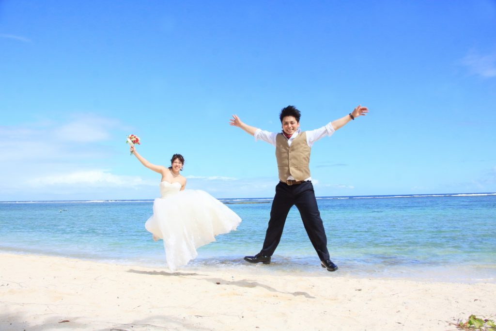 結婚した新郎新婦が海でジャンプ